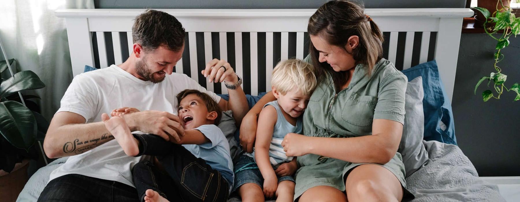 parents play with their children on a bed