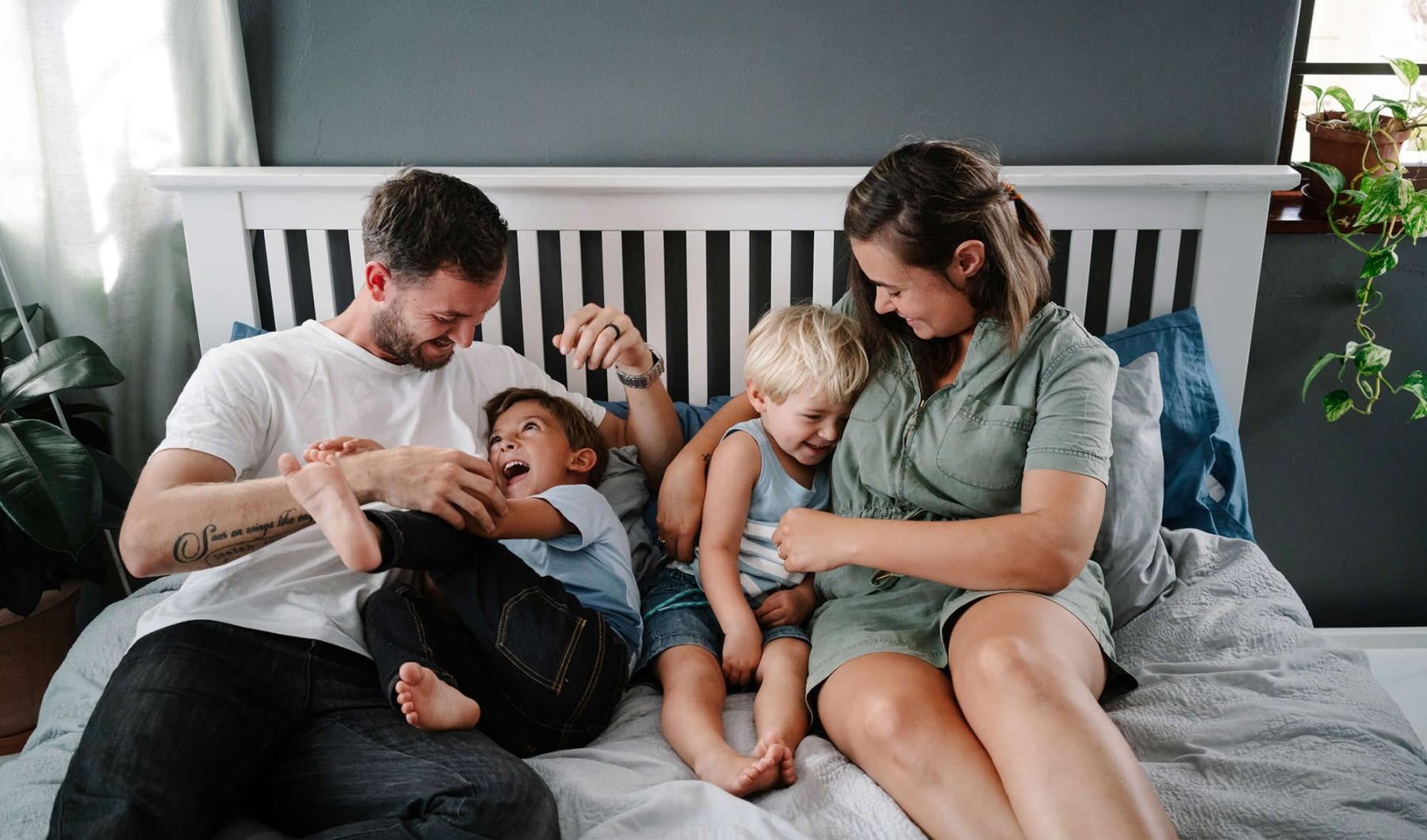 parents play with their children on a bed
